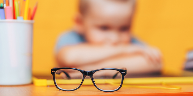 Image of a pair of glasses with a child in the background.